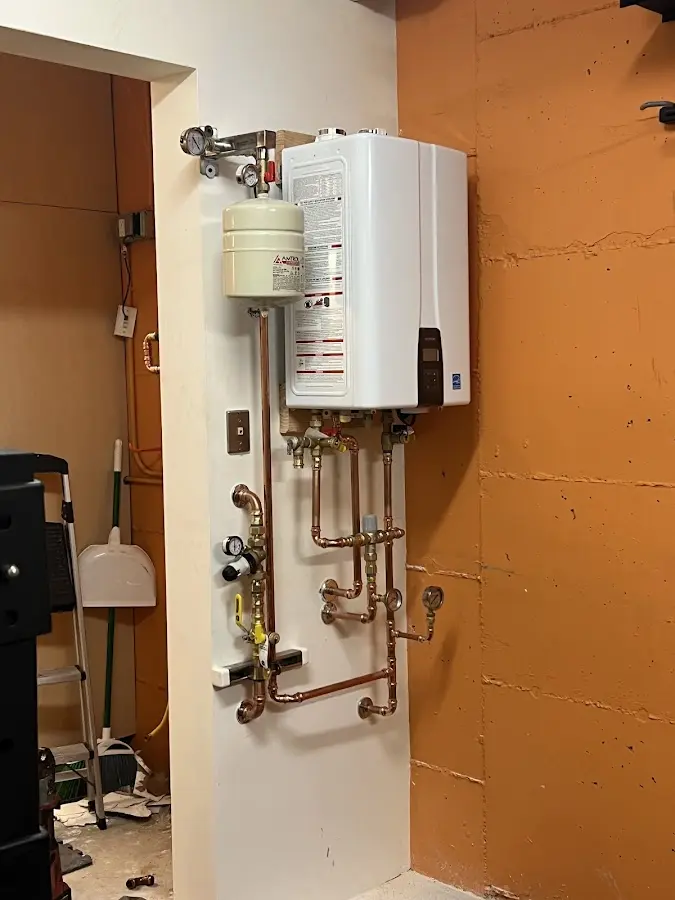 Plumbing technician inspecting water heater connections in Caldwell